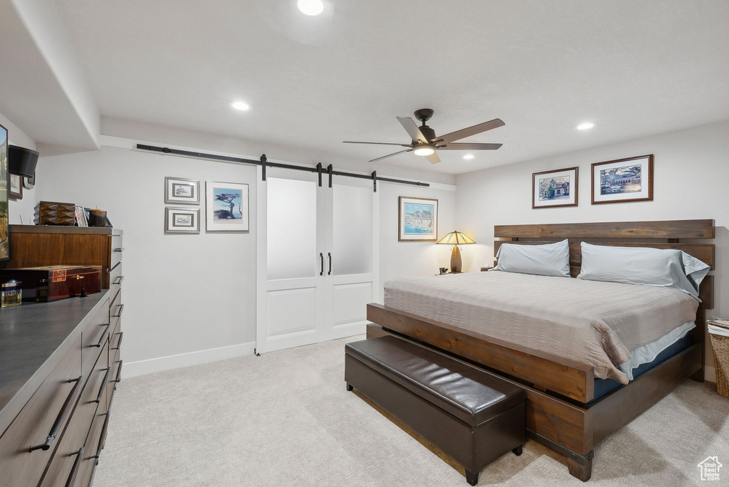 Carpeted bedroom featuring a barn door and ceiling fan