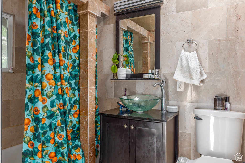 Full bathroom with shower / bath combination with curtain, vanity, toilet, and tile walls