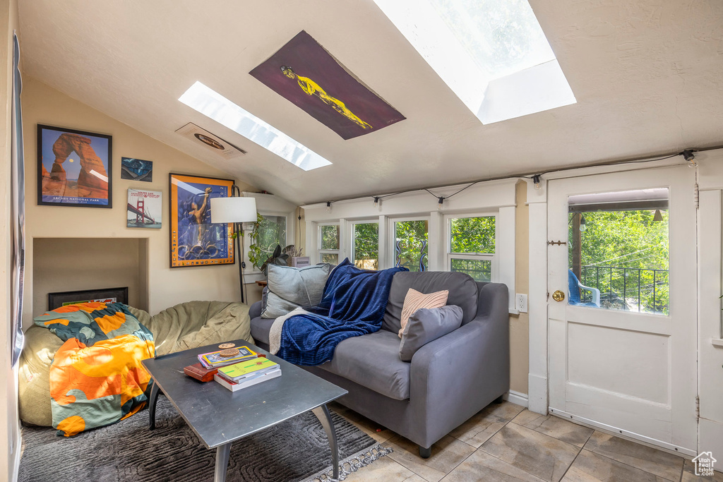 Living room with tile floors and vaulted ceiling with skylight