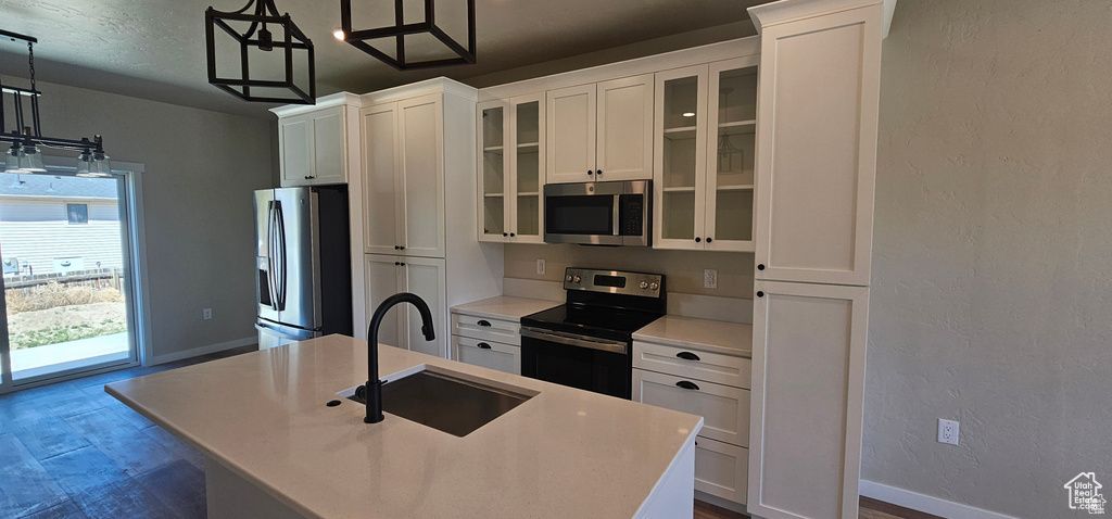 Kitchen with pendant lighting, sink, a kitchen island with sink, white cabinetry, and appliances with stainless steel finishes