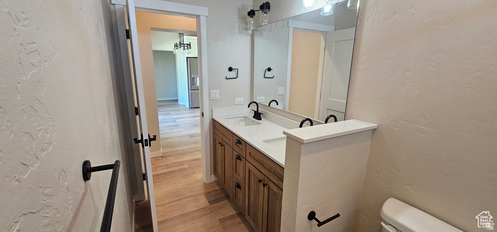 Bathroom featuring double sink, oversized vanity, toilet, and wood-type flooring