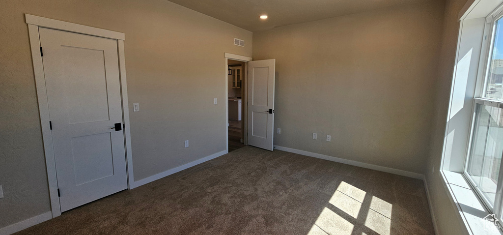 Unfurnished bedroom with dark colored carpet