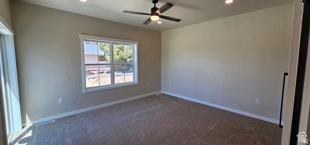 Carpeted spare room featuring ceiling fan