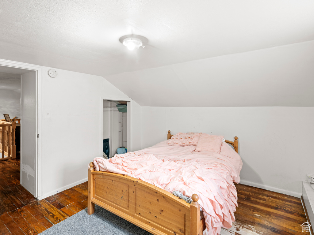 Bedroom with dark wood-type flooring, a closet, and vaulted ceiling