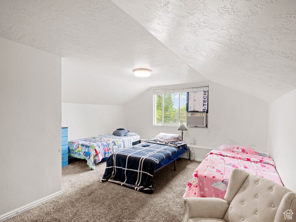 Carpeted bedroom with a textured ceiling and lofted ceiling