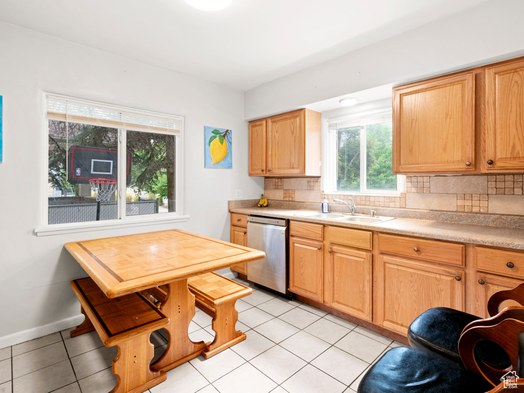 Kitchen featuring sink, tasteful backsplash, stainless steel dishwasher, and light tile floors