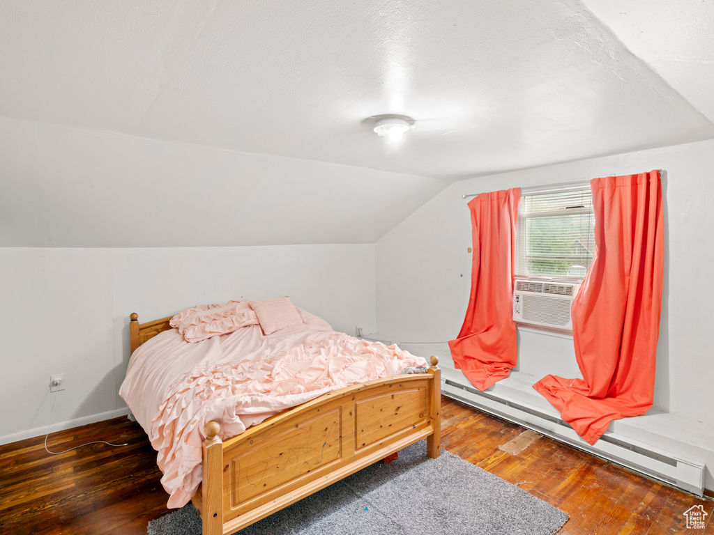 Bedroom with hardwood / wood-style flooring, a baseboard radiator, and lofted ceiling