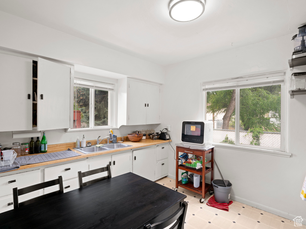 Kitchen featuring white cabinets, sink, and light tile floors