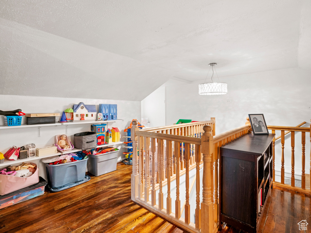 Interior space with vaulted ceiling, a textured ceiling, and dark hardwood / wood-style flooring