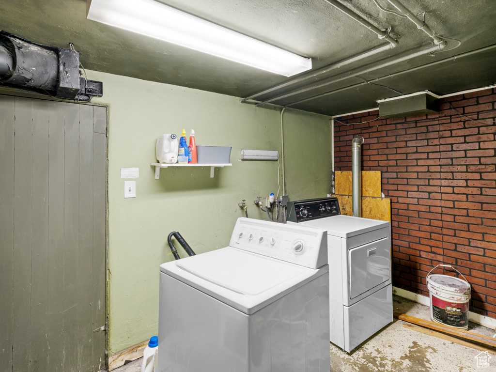 Laundry area featuring independent washer and dryer, brick wall, and hookup for a washing machine