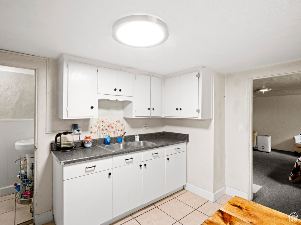 Kitchen featuring sink, white cabinetry, and light tile floors