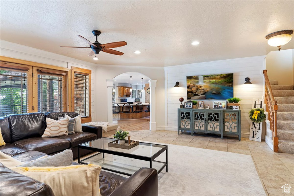 Living room with a textured ceiling, tile flooring, and ceiling fan