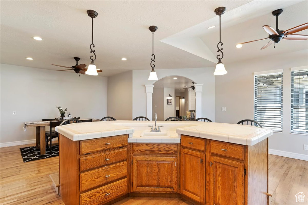 Kitchen featuring hanging light fixtures, a center island, ceiling fan, and light wood-type flooring