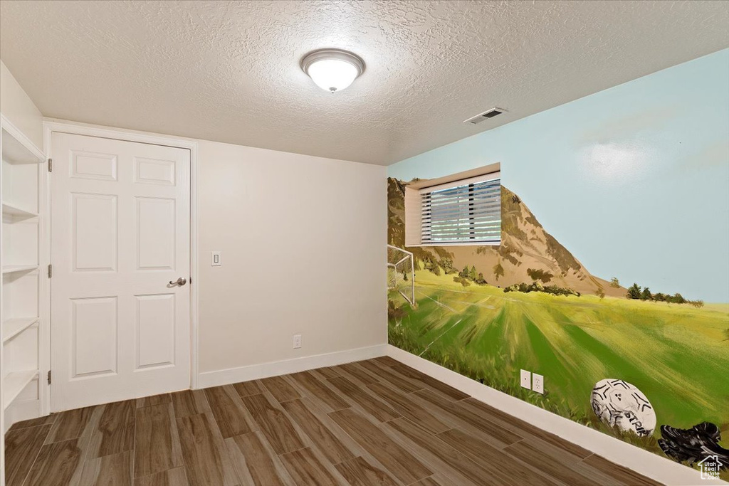 Empty room with a textured ceiling and dark wood-type flooring