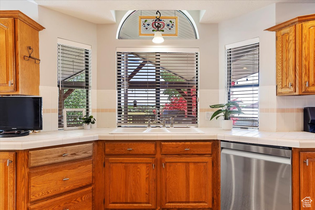 Kitchen with sink, backsplash, dishwasher, and tile counters