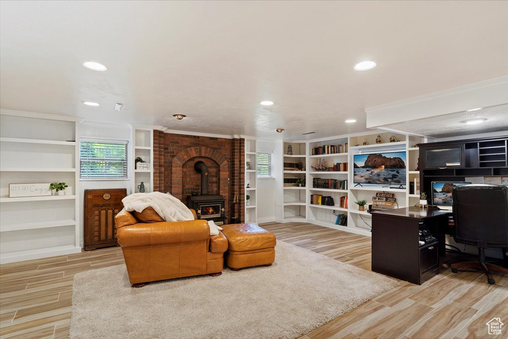 Living room with brick wall, built in features, a wood stove, and light hardwood / wood-style flooring