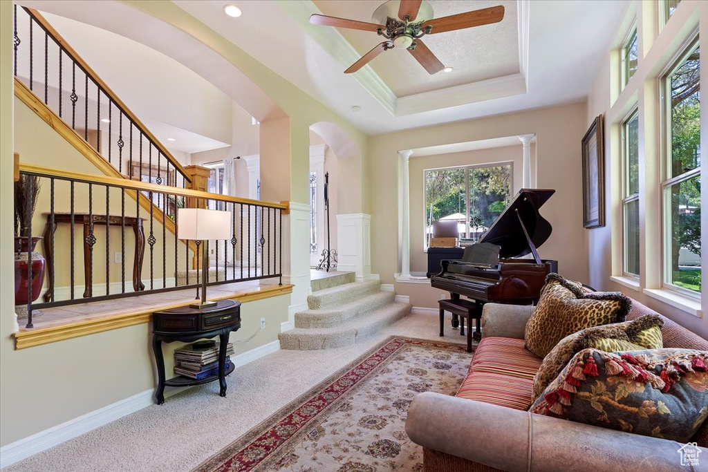 Carpeted living room featuring a tray ceiling and ceiling fan