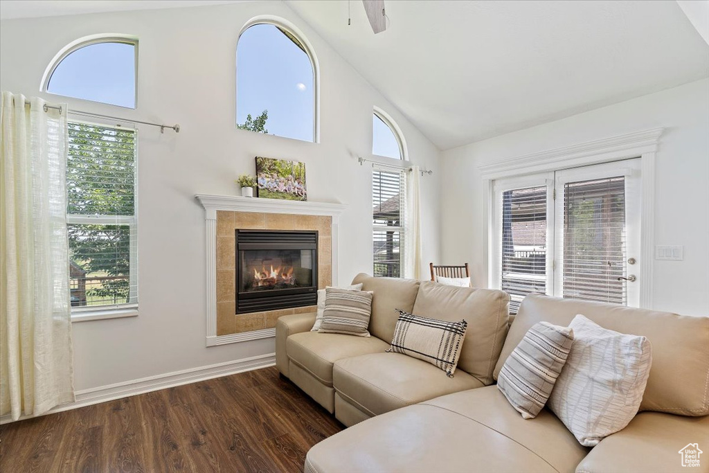 Living room featuring a healthy amount of sunlight, dark hardwood / wood-style floors, a tiled fireplace, and ceiling fan