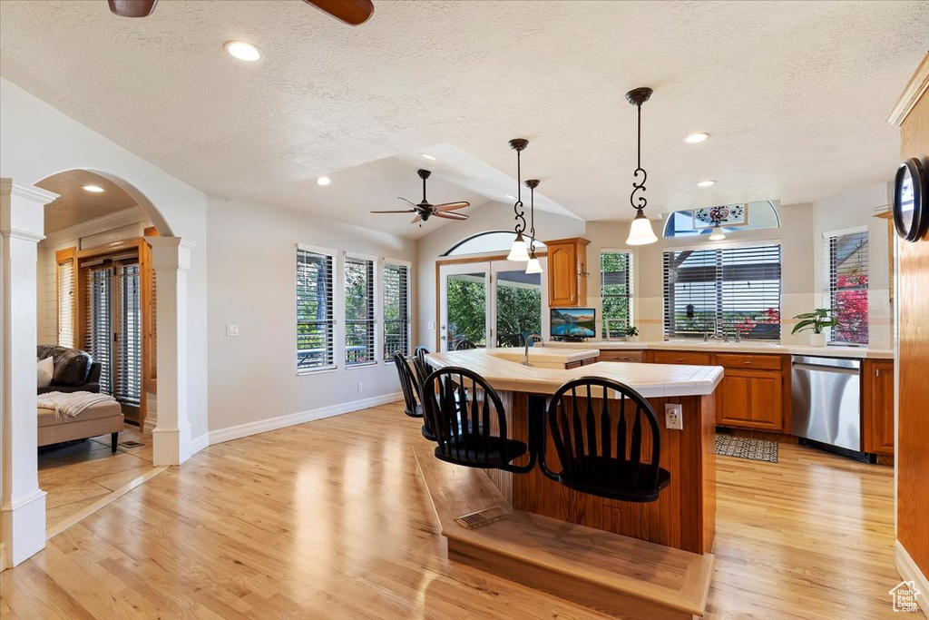 Dining area with ornate columns, ceiling fan, light hardwood / wood-style flooring, and a textured ceiling