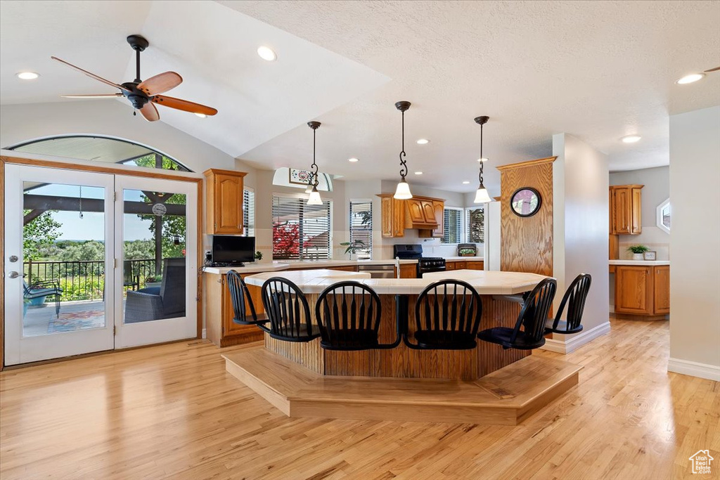 Kitchen with ceiling fan, vaulted ceiling, light wood-type flooring, gas stove, and a kitchen island