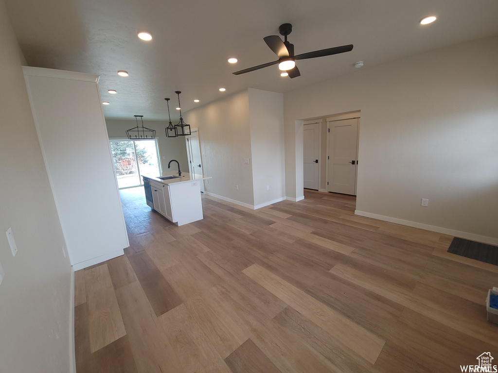 Unfurnished living room featuring ceiling fan, sink, and light hardwood / wood-style floors