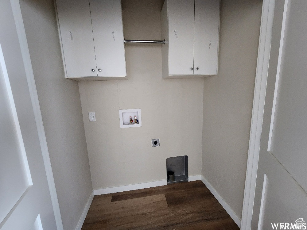 Clothes washing area with hookup for a washing machine, dark hardwood / wood-style flooring, electric dryer hookup, and cabinets