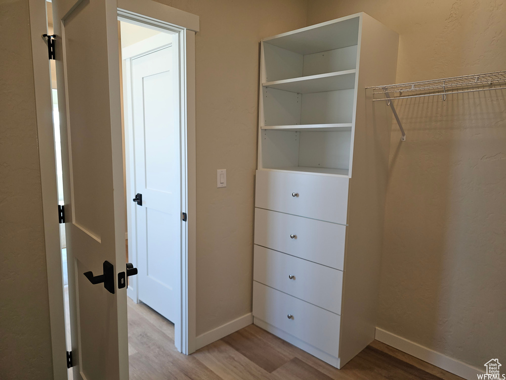 Walk in closet with light wood-type flooring