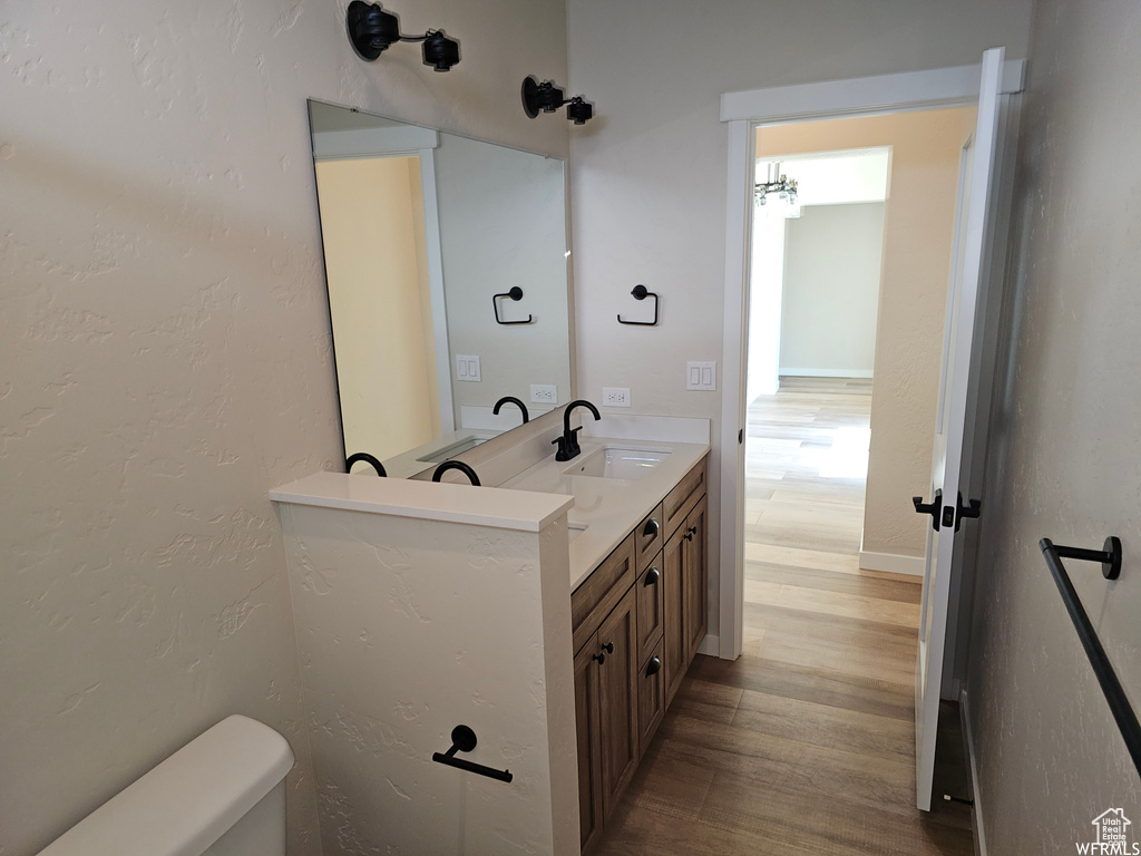 Bathroom featuring double vanity, toilet, and hardwood / wood-style floors