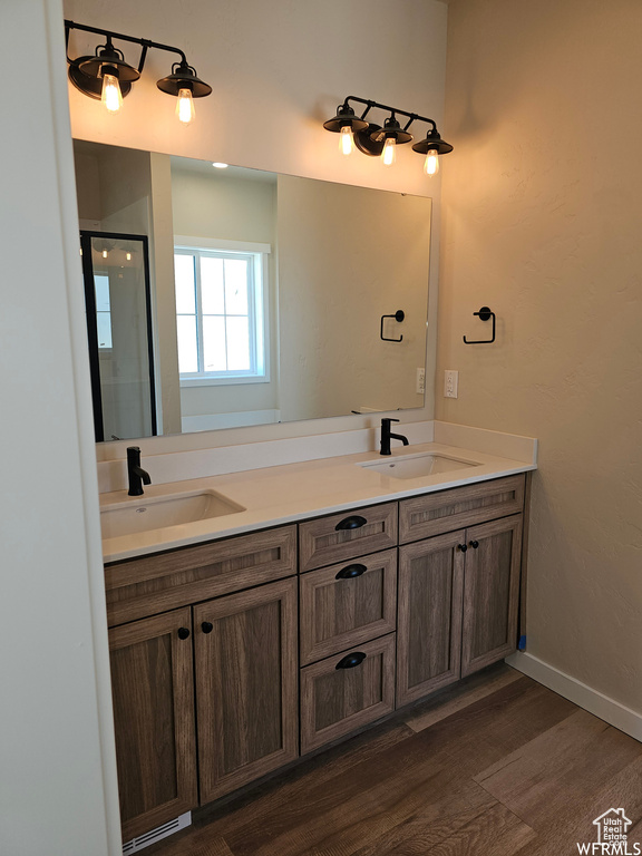 Bathroom with dual sinks, vanity with extensive cabinet space, and hardwood / wood-style flooring