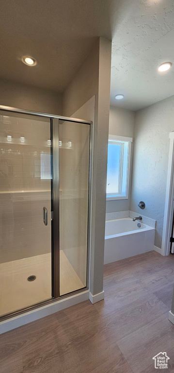 Bathroom with shower with separate bathtub and hardwood / wood-style flooring