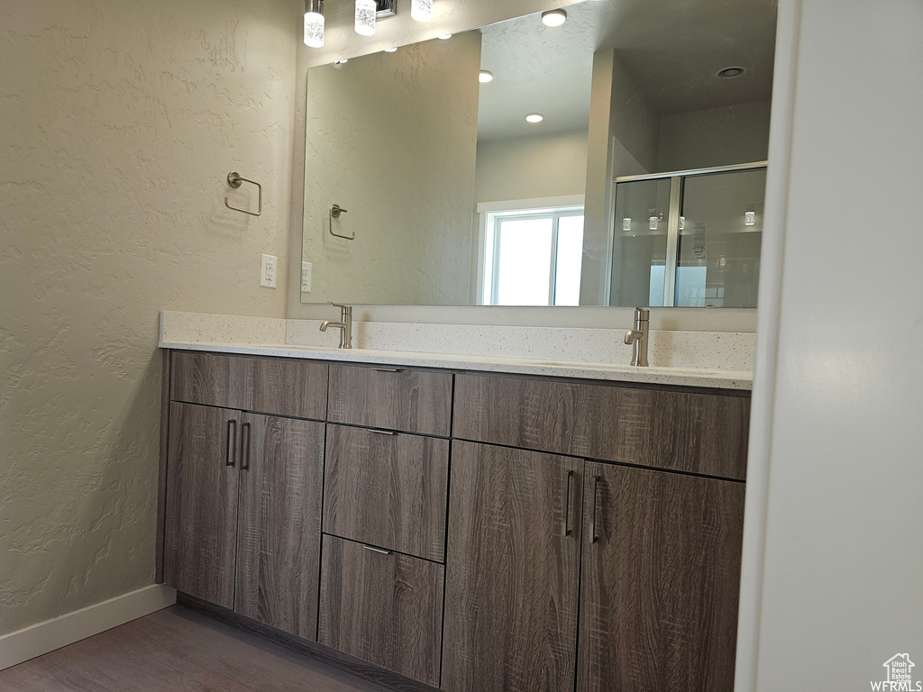 Bathroom with double vanity and wood-type flooring