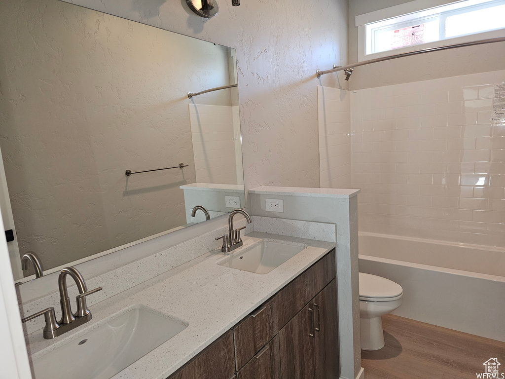 Full bathroom featuring shower / bath combination, double vanity, toilet, and wood-type flooring