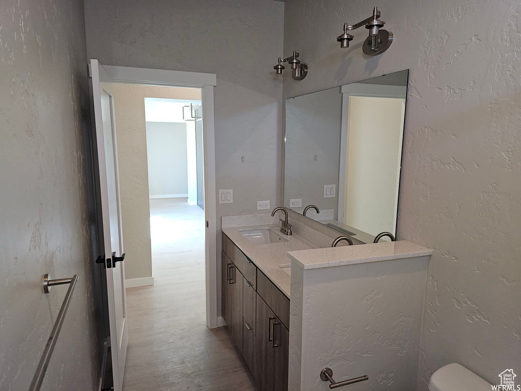 Bathroom featuring dual bowl vanity, toilet, and hardwood / wood-style floors