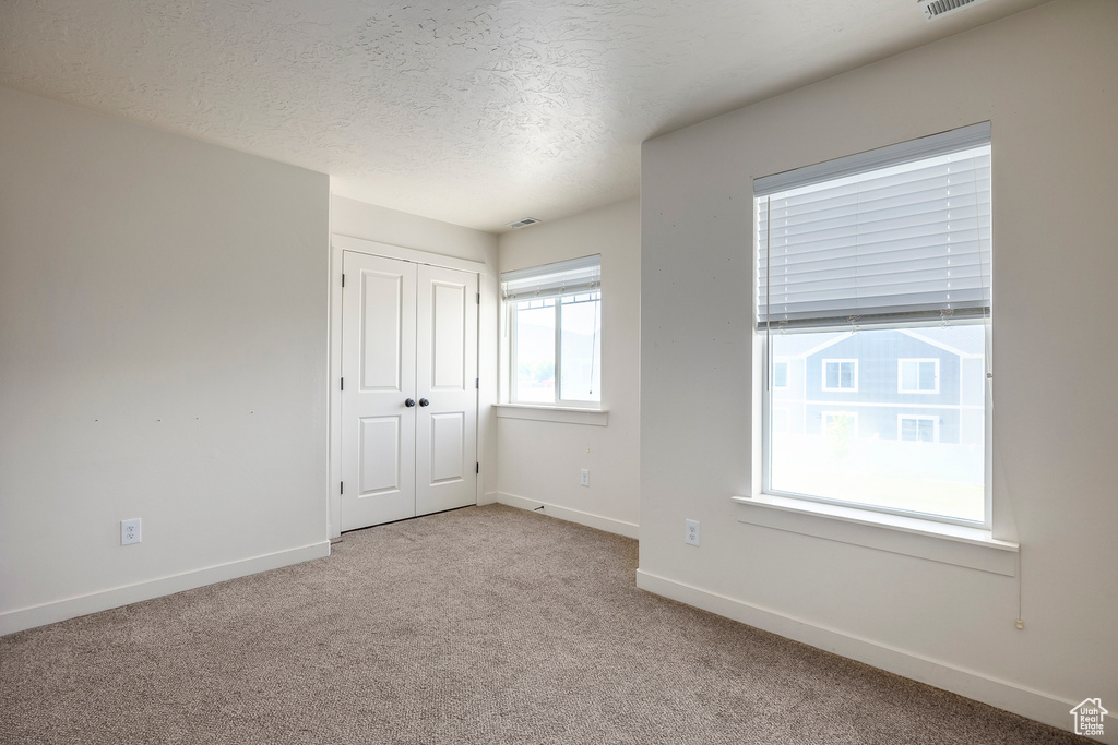 Unfurnished room featuring a textured ceiling and light carpet