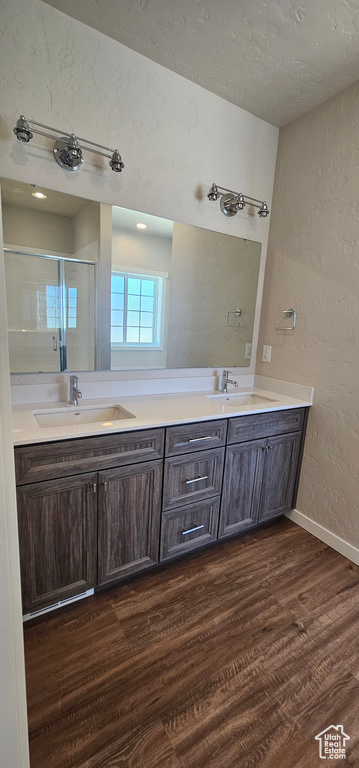 Bathroom with dual vanity, a textured ceiling, and hardwood / wood-style floors