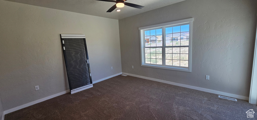 Carpeted spare room featuring ceiling fan