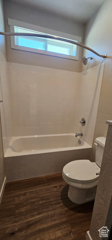 Bathroom with hardwood / wood-style flooring, shower / bath combination, and toilet