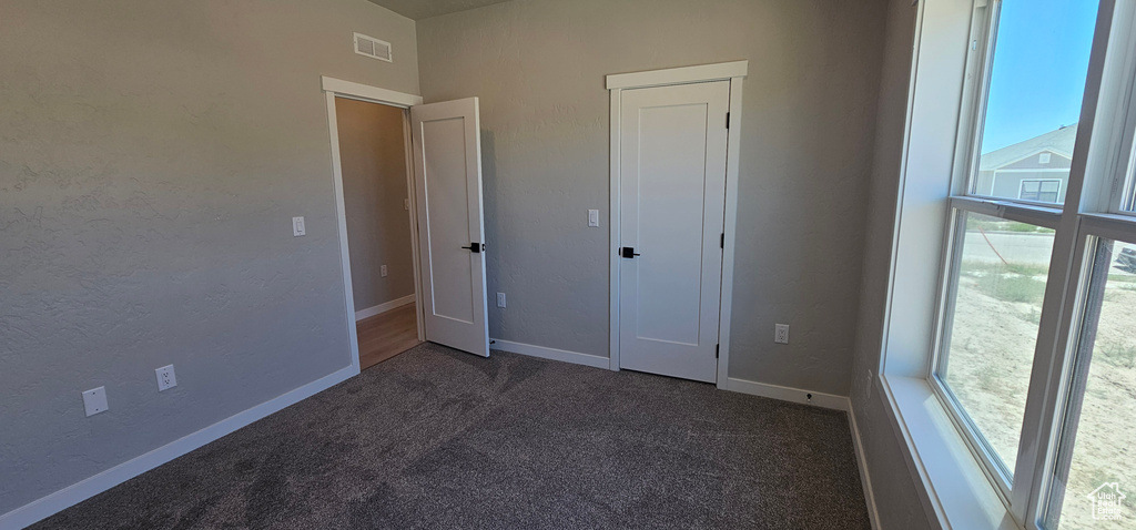 Unfurnished bedroom featuring dark colored carpet