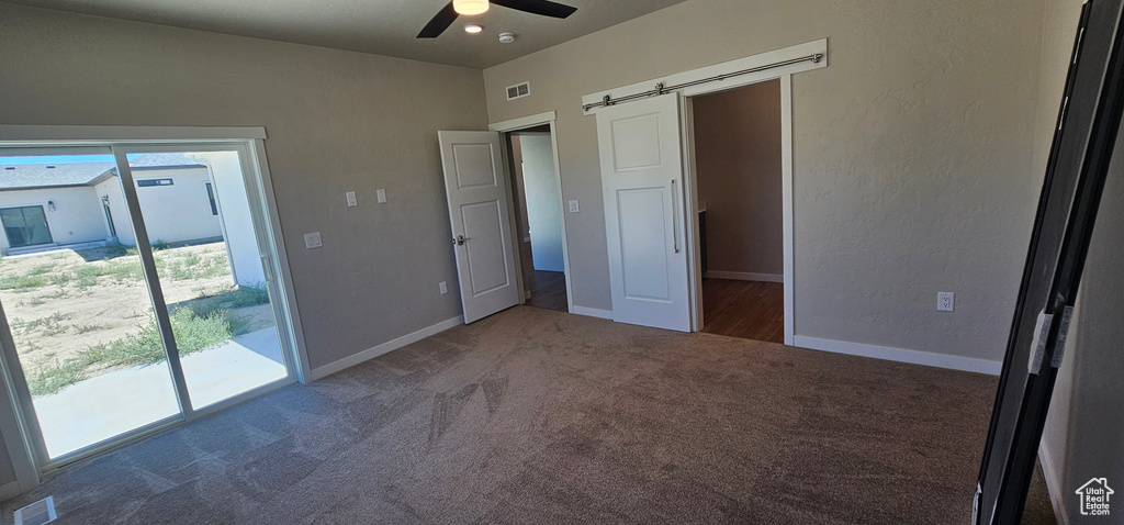 Unfurnished bedroom with access to exterior, carpet, ceiling fan, and a barn door