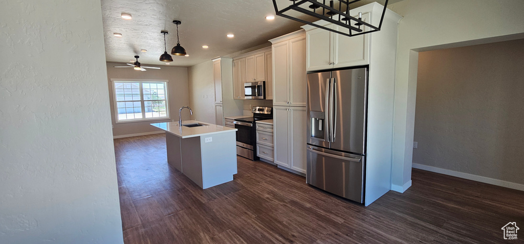 Kitchen with white cabinetry, dark hardwood / wood-style flooring, ceiling fan, an island with sink, and appliances with stainless steel finishes