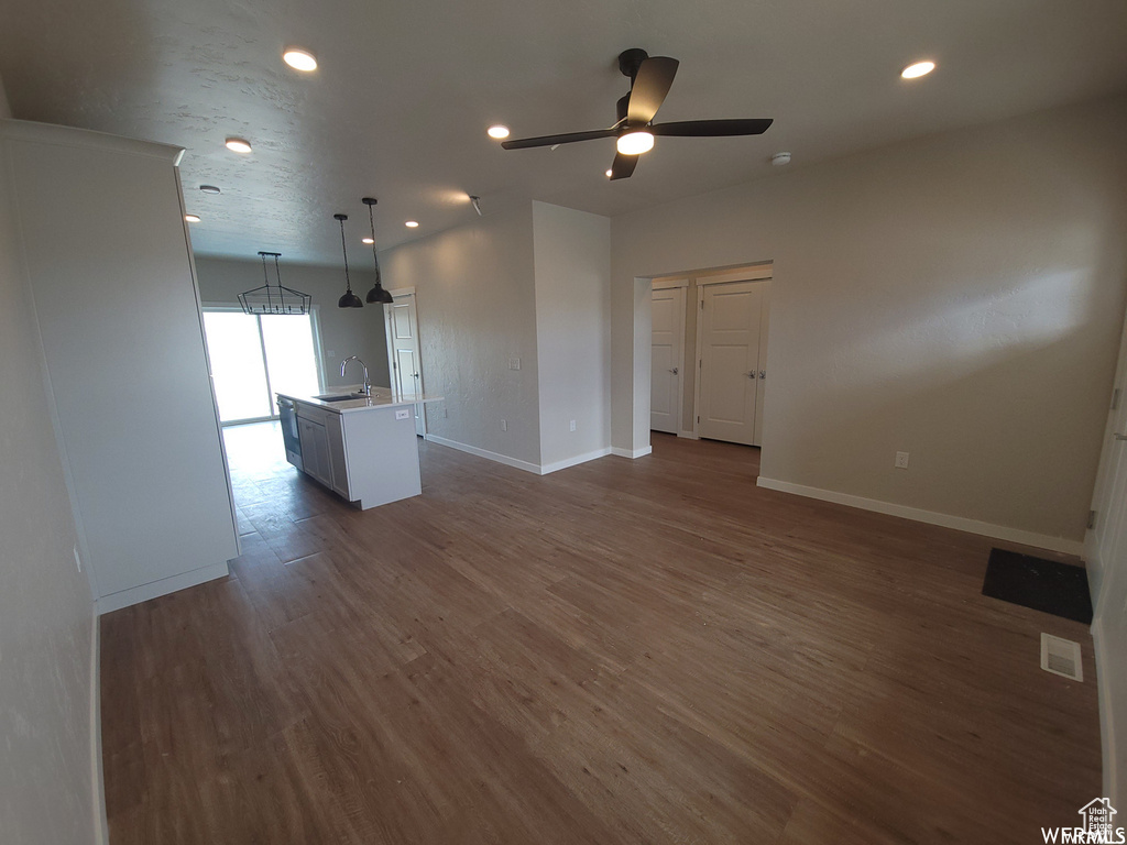 Unfurnished living room featuring sink, ceiling fan, and dark hardwood / wood-style flooring