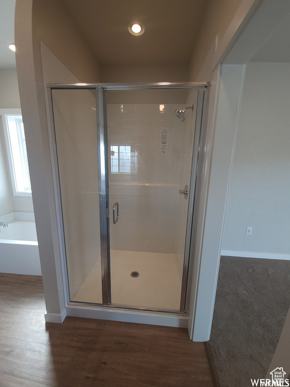 Bathroom with independent shower and bath and wood-type flooring