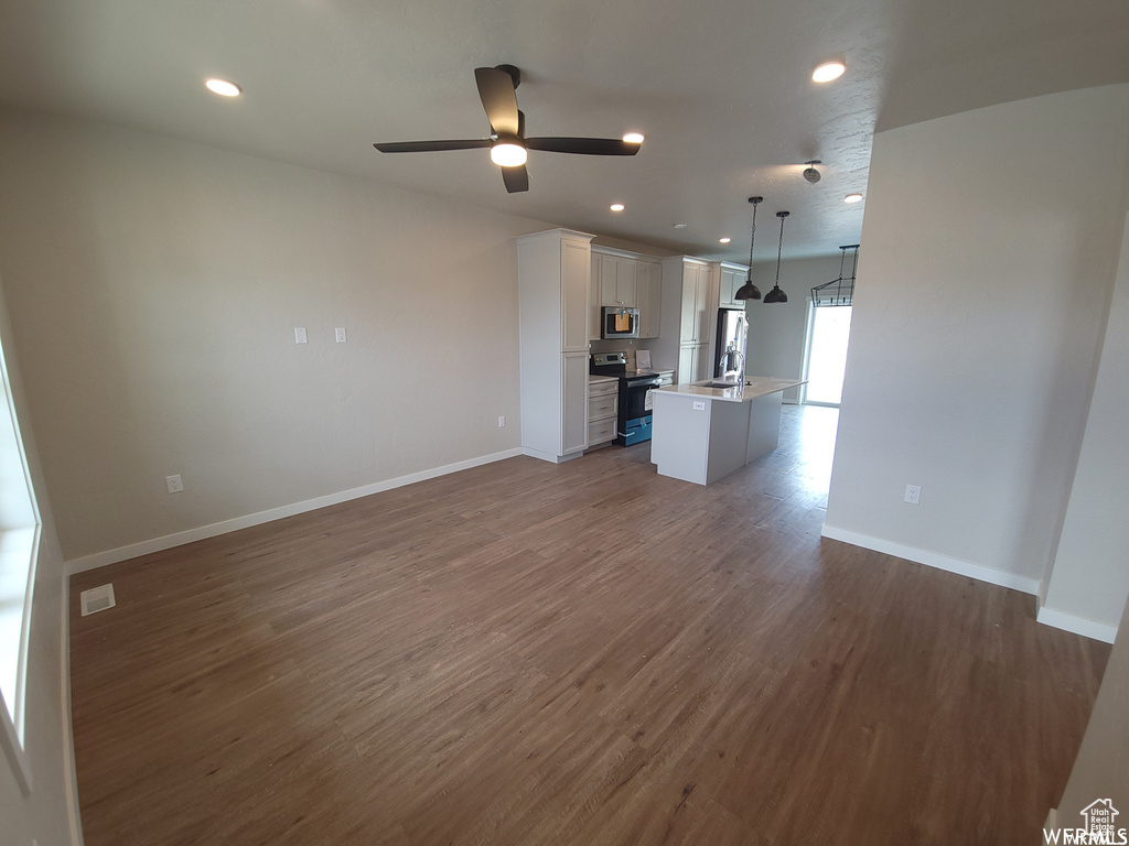 Unfurnished living room featuring ceiling fan, sink, and wood-type flooring