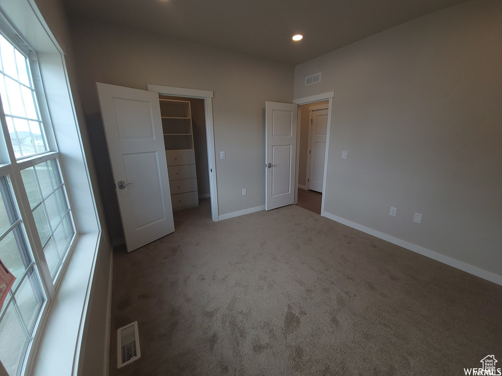 Unfurnished bedroom featuring a spacious closet, a closet, and carpet