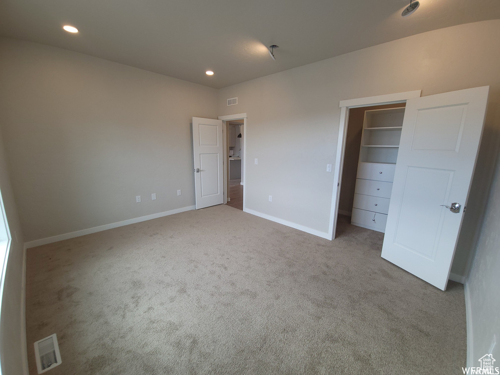 Unfurnished bedroom with a closet, a walk in closet, and carpet flooring