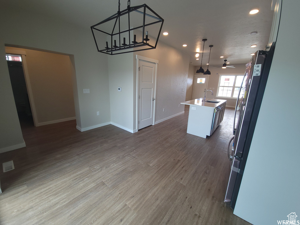 Unfurnished dining area featuring hardwood / wood-style floors, sink, and ceiling fan with notable chandelier