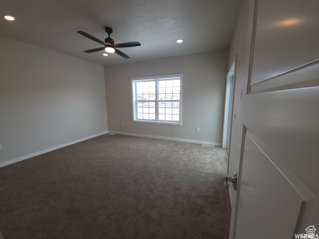 Carpeted spare room featuring ceiling fan