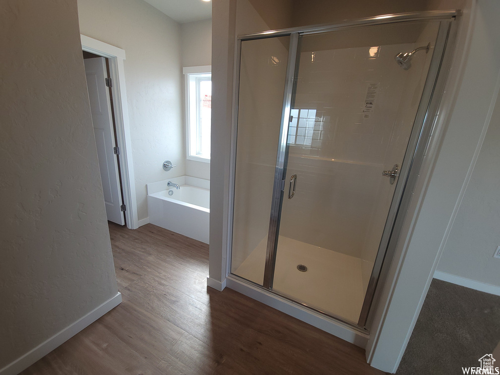 Bathroom with separate shower and tub and wood-type flooring