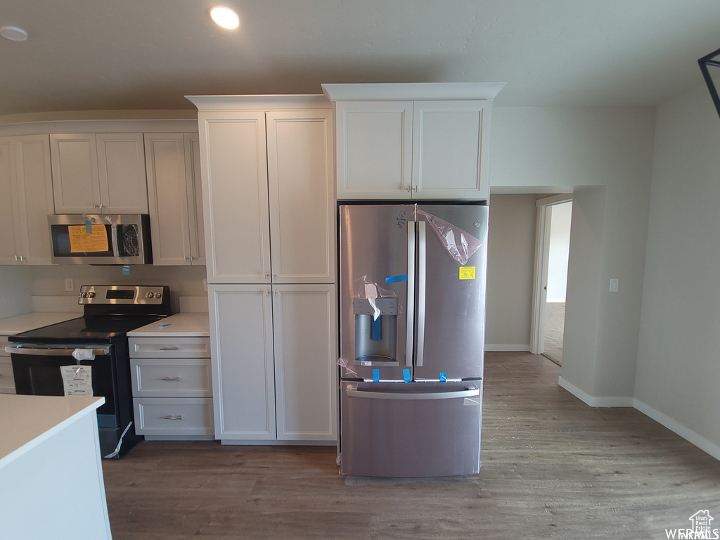 Kitchen featuring light hardwood / wood-style floors, white cabinets, and stainless steel appliances