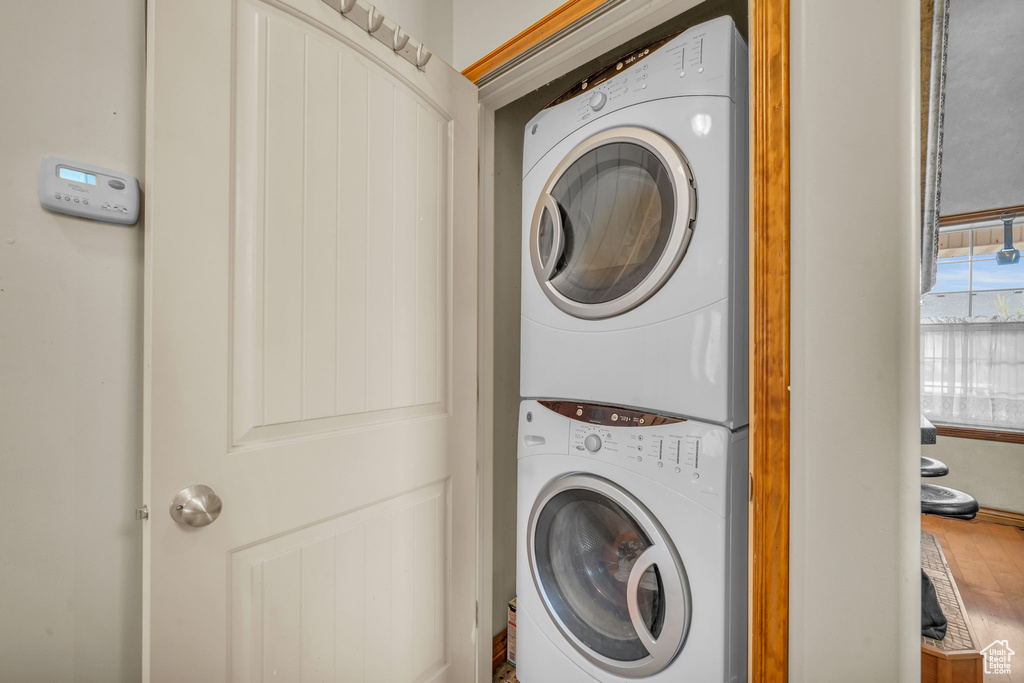 Laundry area featuring wood-type flooring and stacked washer and dryer
